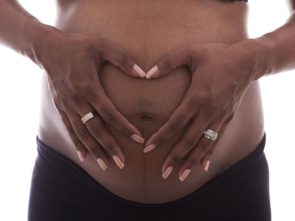 pregnant woman making heart on her belly with her hands