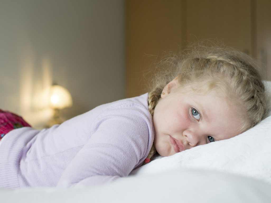 little girl lying in bed looking scared