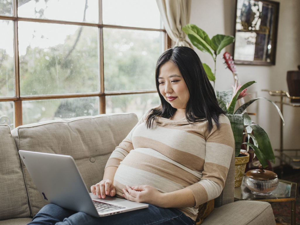 pregnant mom looking at laptop