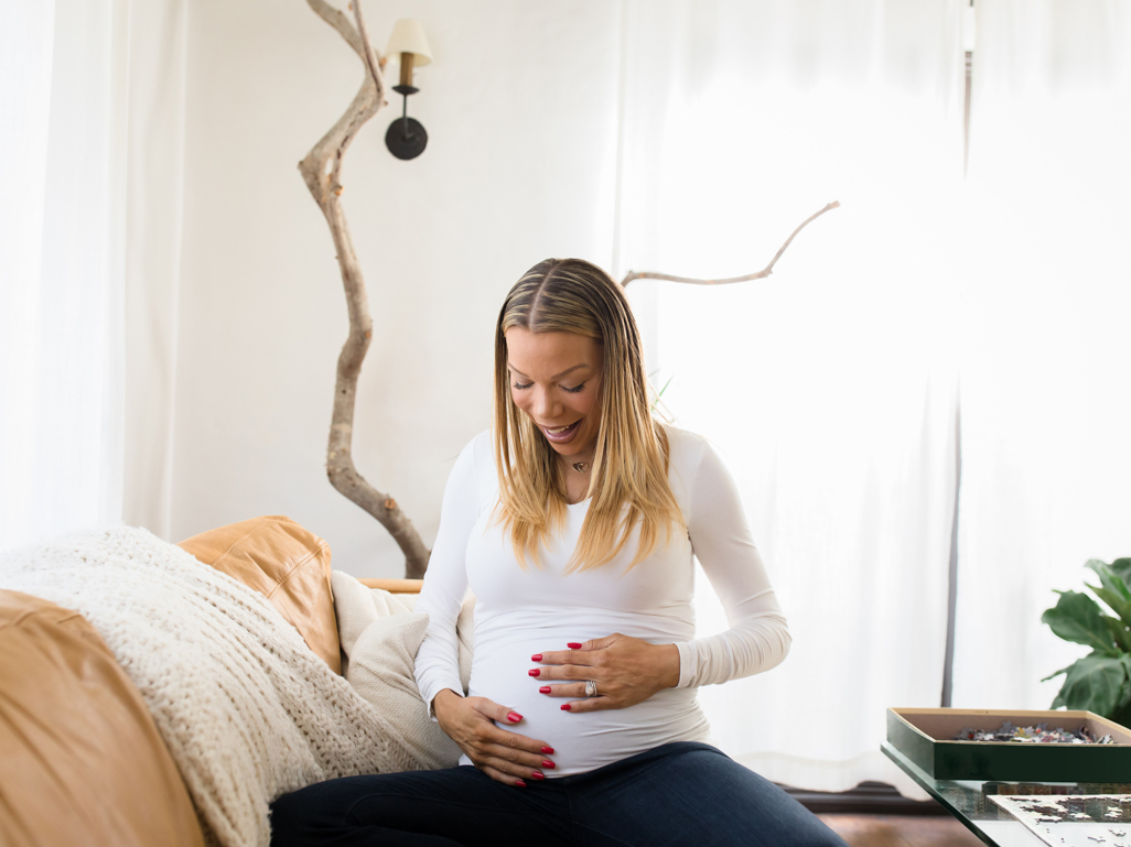 pregnant woman looking down smiling with hands on belly