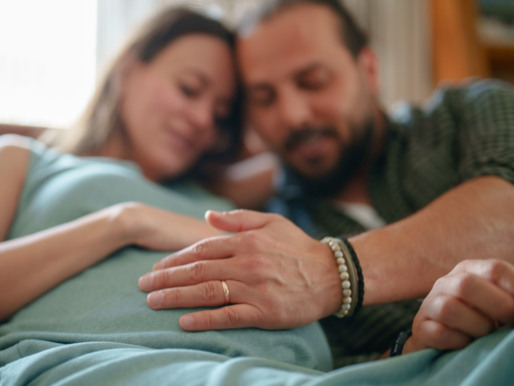 dad's hand gently resting on pregnant mom's belly
