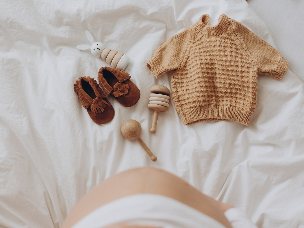 trendy baby clothing and baby items lying on a bed