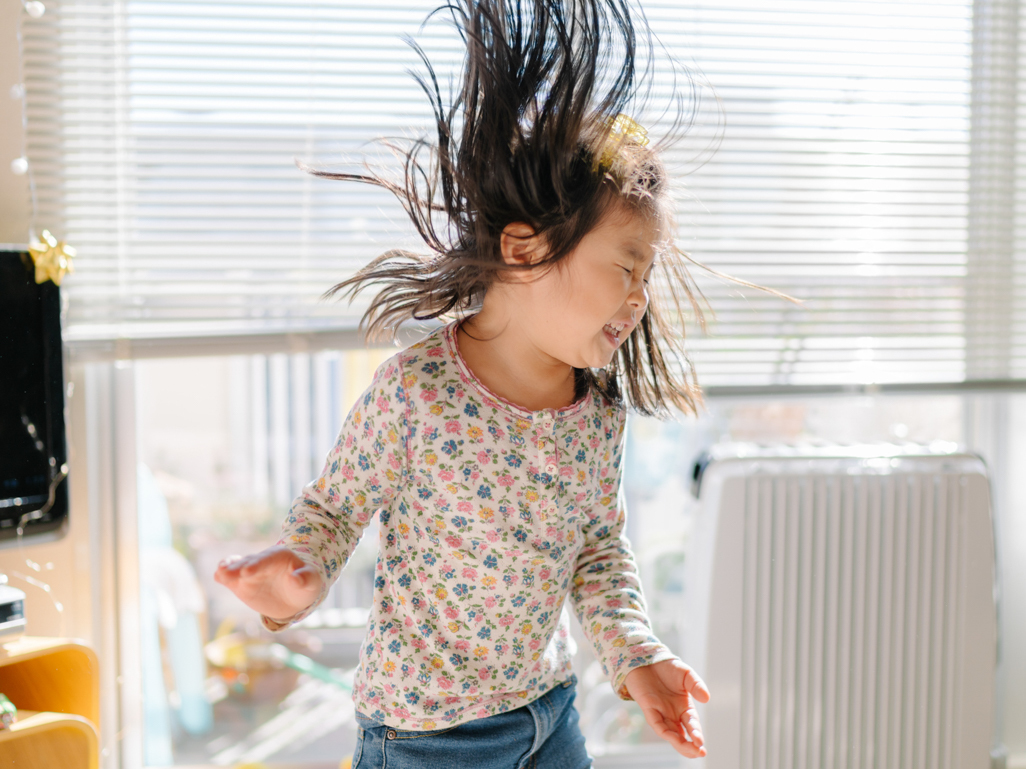little girl dancing happily while swinging hair