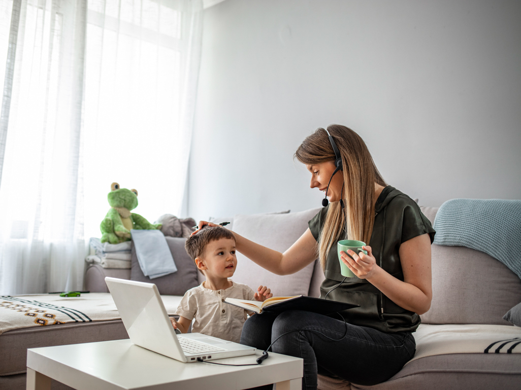 mother smiling at child while working at a laptop