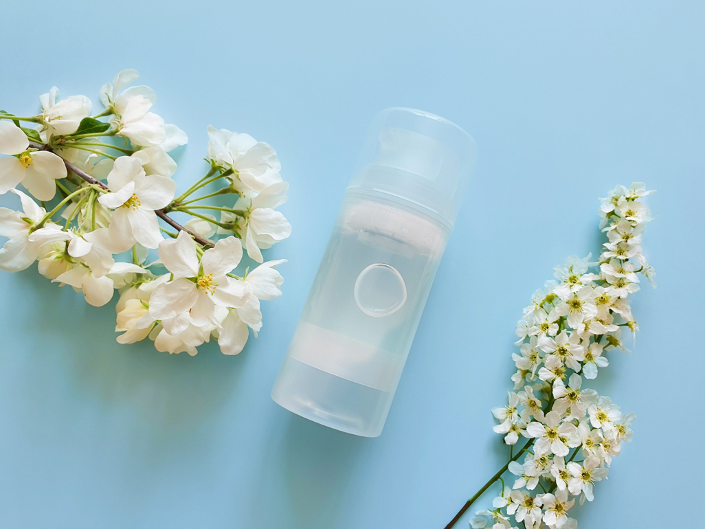 A bottle of lube on a blue background and surrounded by flowers 