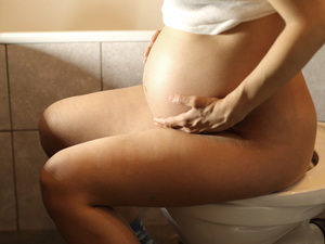 pregnant woman sitting on toilet