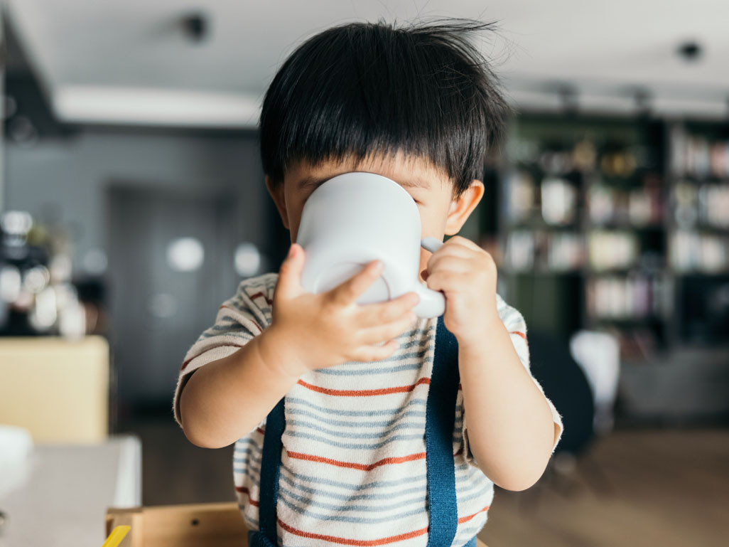 A toddler drinking from a mug
