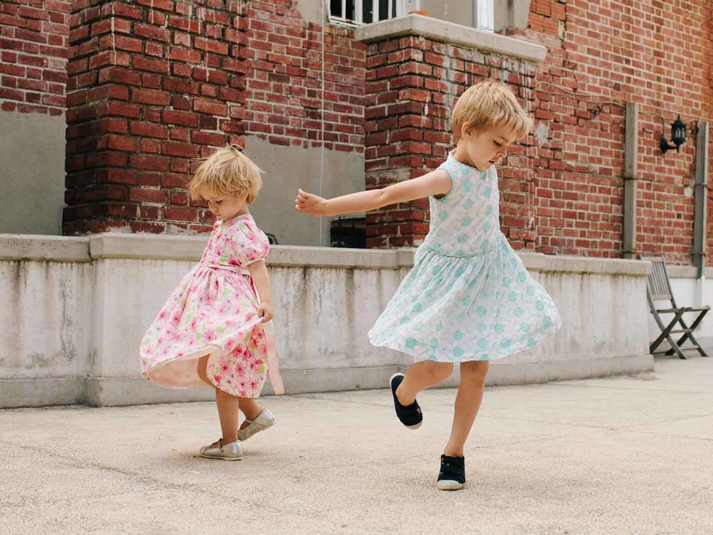 Two children wearing dresses and playing together