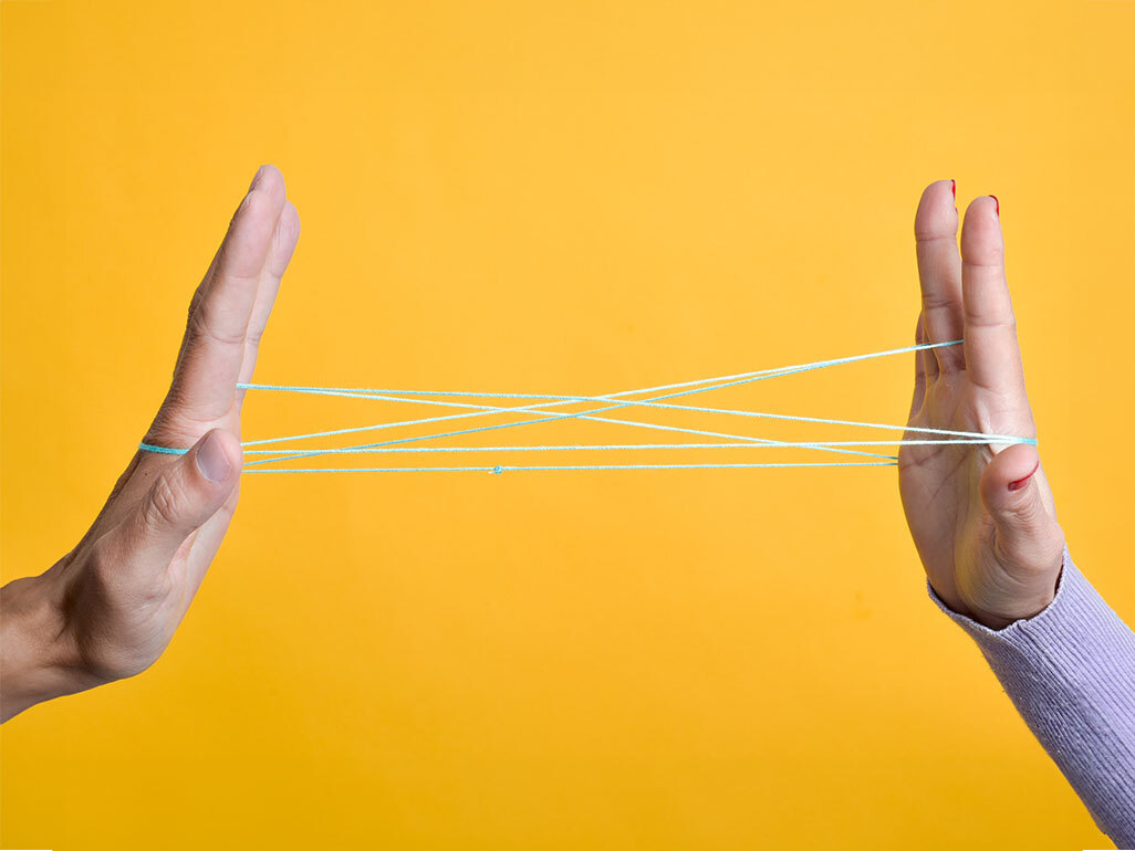 two hands connected by interlaced string