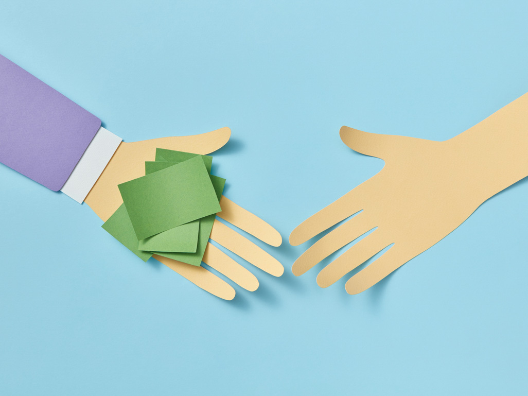 paper cutout art of one hand giving cash to another