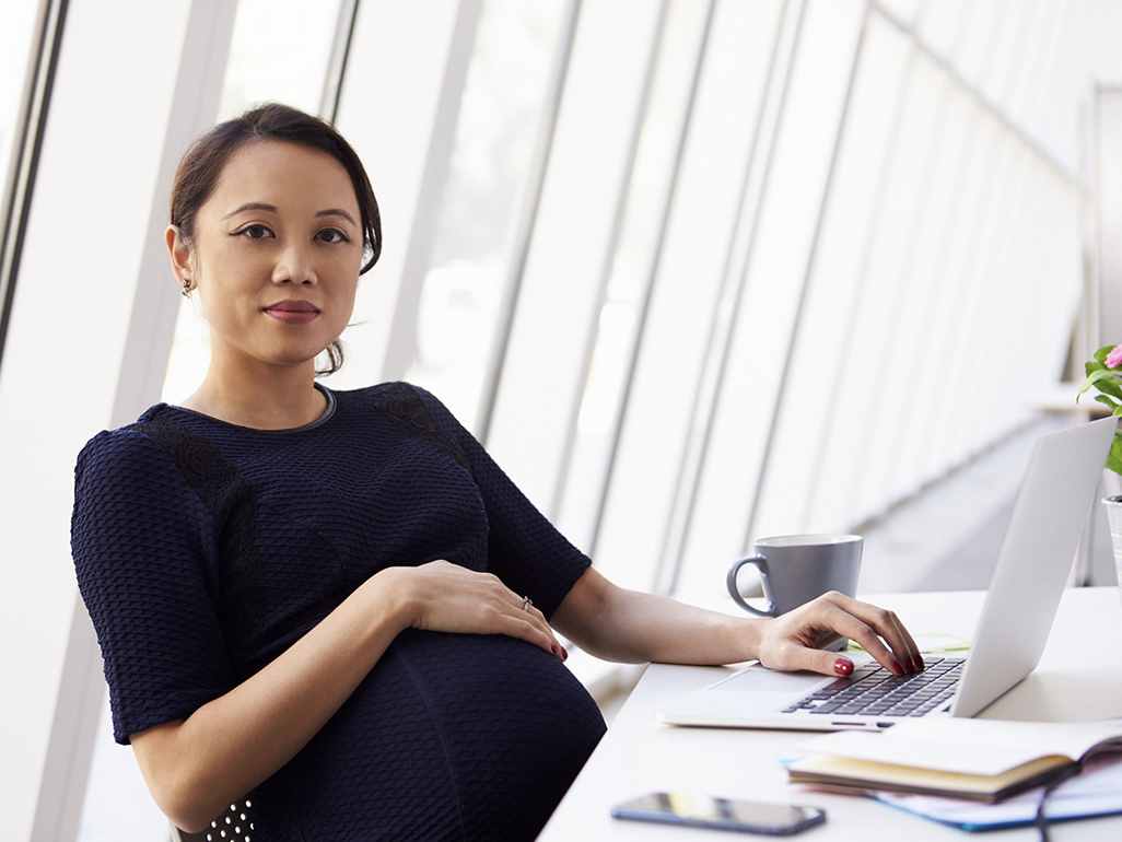 pregnant woman sitting at desk in office setting